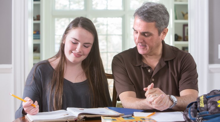 daughter and father working at table
